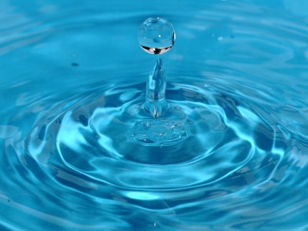 Ein Wassertropfen fällt in klares, blaues Wasser
