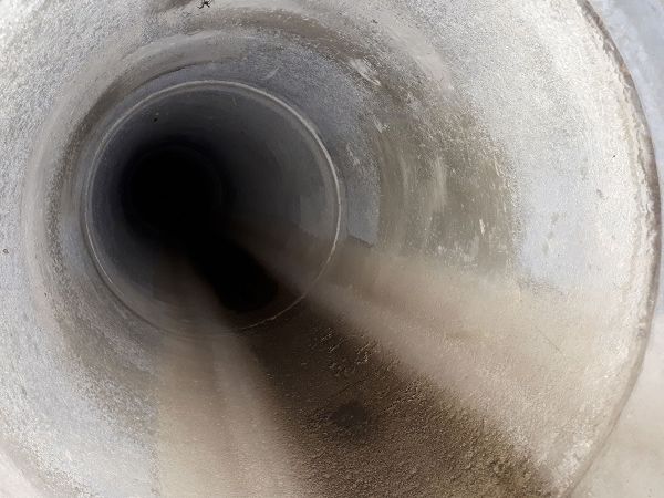 Blick in eine großes leeres Betonrohr, das als Überlaufrohr auf einer Kläranlage dient