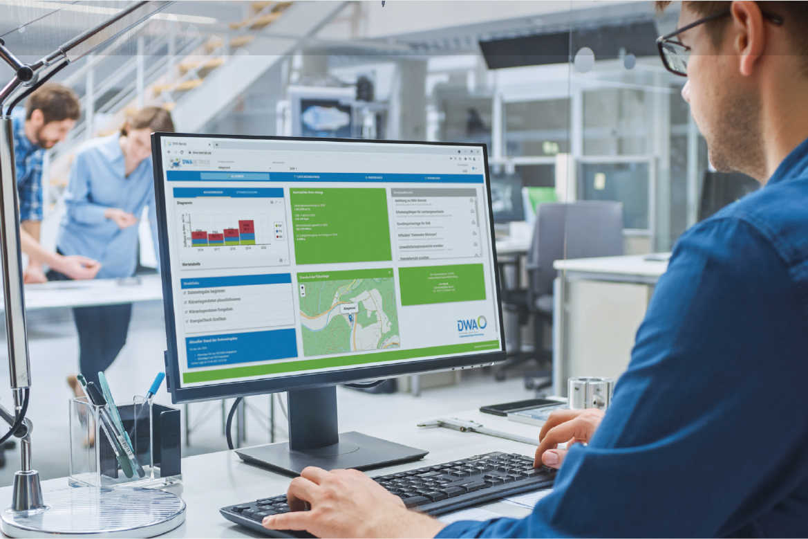 Mann am Schreitisch sitzt am PC auf dem das Online-Portal DWA Betrieb geöffnet ist.